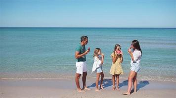 famille heureuse mangeant de la pastèque sur la plage. video
