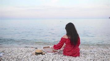 mujer haciendo un picnic con pizza en la playa video