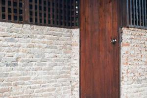 Brown painted vintage wooden door set into left side of old brick wall photo