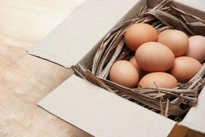 Fresh chicken eggs in paper box on the wooden table photo