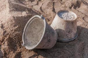 Plastic bucket with cement placed on on the sand at construction site photo