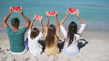 Happy family eating watermelon on the beach.