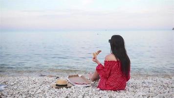 mujer haciendo un picnic con pizza en la playa video