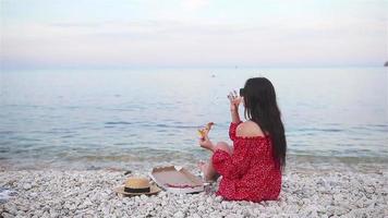 mujer haciendo un picnic con pizza en la playa video