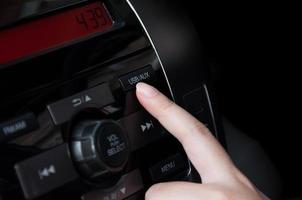 Woman finger pressing button USB AUX detail on a car's dashboard, car interior photo