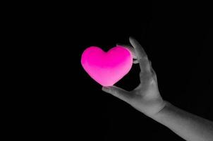 Woman hand holding blank pink heart on dark background,Symbol of love or dating photo