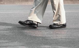 man's legs in black combat boots walking on sidewalk photo