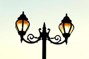 Beautiful vintage Street antique style lamp post with effect of shine from low light of sunset photo