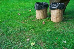 Trash bin made of bamboo baskets on green grass at public park photo