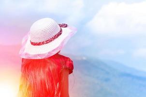 joven niño niña rojo camisa con vestir sombrero en naturaleza antecedentes en el azul cielo. un símbolo de liderazgo, éxito y libertad y viaje foto