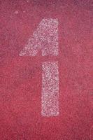 Number one on running track. White track number on red rubber racetrack, texture of running racetracks in stadium photo