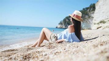 Young beautiful woman on white sand tropical beach. Caucasian girl in hat background the sea video