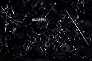 Abstract of Used Metallic knot screw nuts and nail bolts on dark background photo