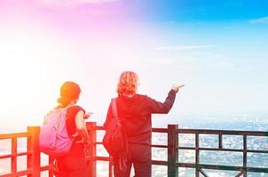 viaje y turismo. el espalda ver de el mujer mochilero turista con disfrutando ver juntos en paisaje urbano el cielo y nubes foto