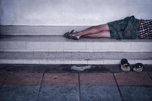 Vagabundo hombre sucio duerme en el calle en el sombra de el edificio. foto