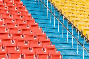 asientos vacíos de color naranja y amarillo en el estadio, filas de asientos en un estadio de fútbol foto