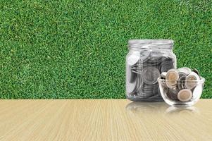 coins in a glass jar on Wood floor ,savings coins - Investment And Interest Concept saving money concept, growing money on piggy bank. isolated on grass background photo