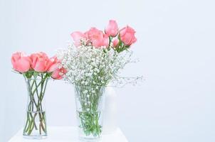 bunch of pink rose eustoma flowers in glass vase on white background photo
