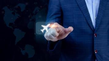 Businessman pointing finger touching to select flight by pressing touch screen airplane button with world map background,Business Airplane transportation concept photo