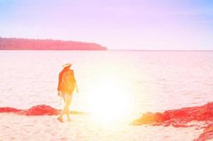 young woman traveler put the hat with rucksack backpacks on sea beach enters the sea photo