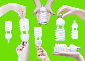 Energy saving concept. Woman hand holding light bulb on green background photo