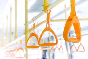 Yellow bus handle on ceiling for standing passenger, public transportation train handrail interior at Thailand photo