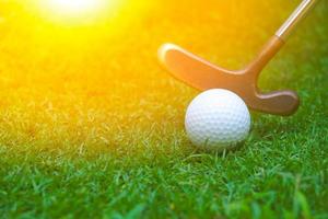 Golf balls and clubs are placed on the lawn.Golf club hitting a white golf ball with green grass. photo