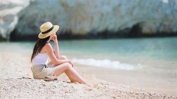 Young beautiful woman on white sand tropical beach. Caucasian girl in hat background the sea video