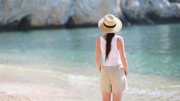 Young beautiful woman on white sand tropical beach. Caucasian girl in hat background the sea video