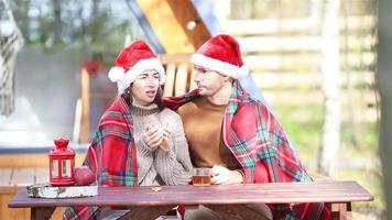 Young couple in red santa hat sitting on the wooden old table video