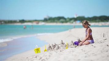 liten flicka på tropisk vit strand framställning sand slott video