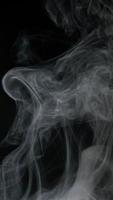 Slow motion vertical video of white smoke, fog, mist, vapor on a black background.