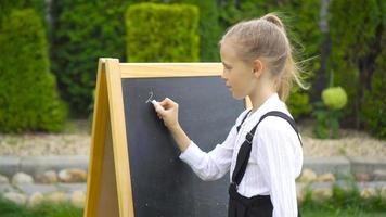 gelukkig weinig schoolmeisje met een schoolbord buitenshuis video