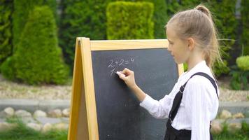 Happy little schoolgirl with a chalkboard outdoor video