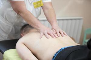 The doctor makes a back massage to a man patient. photo