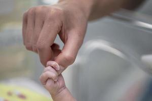 The hand of an adult holds the hand of a newborn child. photo