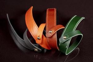 A group of multi-colored leather belts on a black background. photo