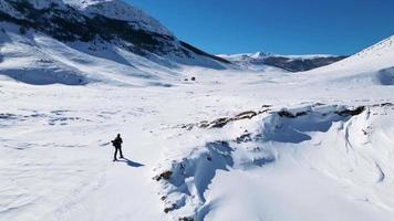 aéreo zumbido ver de solo caminante caminando en el montañas durante el invierno. nieve blanco paisaje y alpinista estilo de vida. video