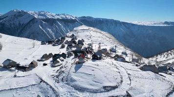 aéreo zumbido ver de montaña pueblo durante invierno. nieve blanco paisaje y alpinista estilo de vida. video