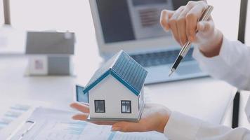 Immobilienmakler-Agent präsentiert und berät den Kunden bei der Entscheidungsfindung, unterzeichnet einen Versicherungsvertrag, kauft und verkauft ein Hausmodell, ein Hypothekendarlehensangebot für und eine Hausversicherung video