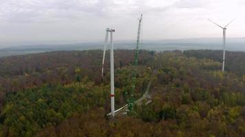 Drönare video av en vind turbin konstruktion webbplats med tunga kran i en skog i Tyskland under de dag
