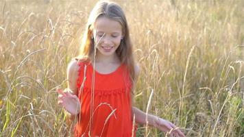 hermosa niñita rubia, tiene cara sonriente alegre y divertida, vestido rojo video