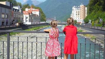 pequeno meninas em a aterro do uma montanha rio dentro uma europeu cidade. video