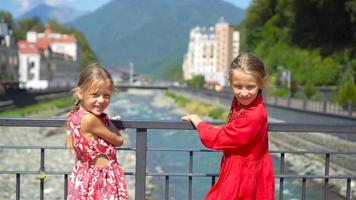 vue arrière des filles sur le quai d'une rivière de montagne dans une ville européenne. video