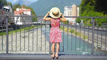 Little girl at hat on the embankment of a mountain river in a European city. video