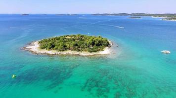dar video van een klein eiland in turkoois water uit de kust van istrië genomen gedurende de dag