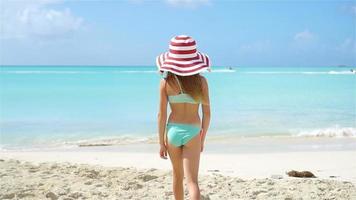 carino poco ragazza nel cappello a spiaggia durante caraibico vacanza video