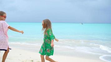 Zwei kleine glückliche Mädchen haben viel Spaß am tropischen Strand und spielen zusammen video