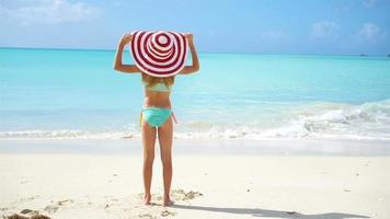 carino poco ragazza nel cappello a spiaggia durante caraibico vacanza video