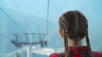 adorable content peu fille dans le cabine sur le câble voiture dans montagnes dans le Contexte de belle paysage video